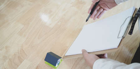 Businessman showing the document and house model on the table, symbol of home insuranceの写真素材