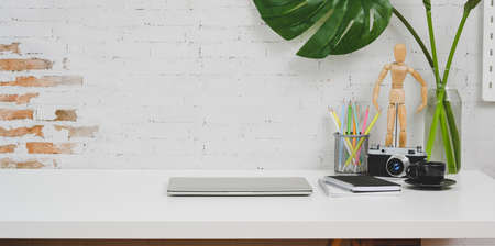 Comfortable designer workplace with camera, laptop computer and office supplies on white table with copy spaceの写真素材