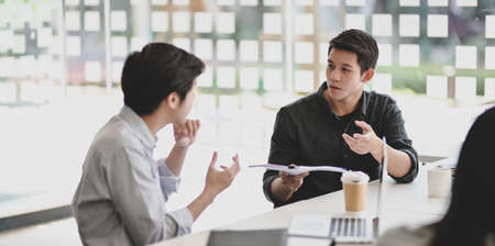 Young professional businessman explaining his idea to his coworkers with tabletの写真素材