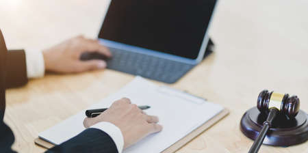 Close-up view of male legal advisor working on a laptop and providing legal document for his clientの写真素材