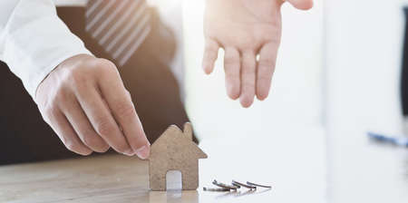 Professional businessman showing a house model on the table, symbol of home insuranceの写真素材