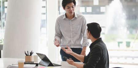 Two businessmen exchanging their idea about the progress of the projects in the modern office roomの写真素材
