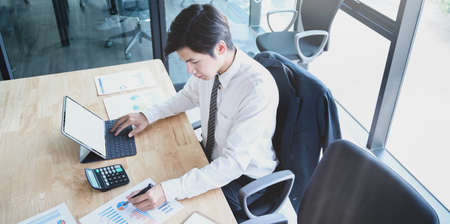 Professional male accountant compiling and analysing financial information to his client while using tabletの写真素材