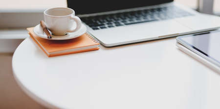 Minimal comfortable workplace with laptop computer and coffee cup on white table with copy spaceの写真素材