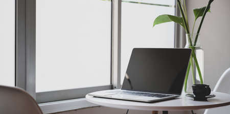 Modern workplace with open laptop, coffee cup and office supplies in comfortable cornerの写真素材