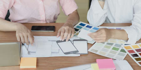 Cropped shot of professional UI web developers discussing on the smartphone template projectの写真素材