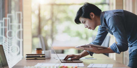 UX web developer working on his project about UX template while using laptop computer and tabletの写真素材