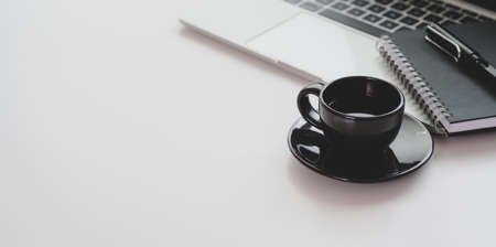 Trendy workplace with black coffee cup and laptop computer with copy space on white tableの写真素材