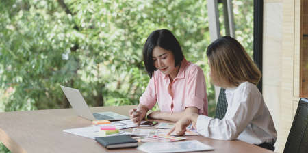 Two professional UI web developers discussing on the smartphone template project while using laptop computerの写真素材