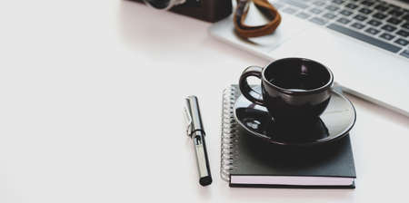 Trendy workplace with black coffee cup and laptop computer with copy space on white tableの写真素材