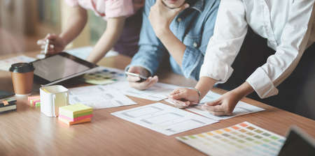 Group of young professional UI graphic designer discussing on their smartphones templates togetherの写真素材