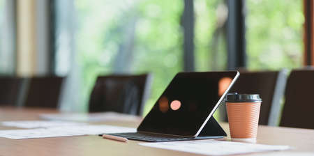 Modern office room with tablet, a cup of coffee and document on wooden table in comfortable atmosphereの写真素材