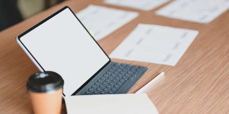 Modern workplace with tablet and a cup of coffee on wooden table with smartphone templates documentの写真素材