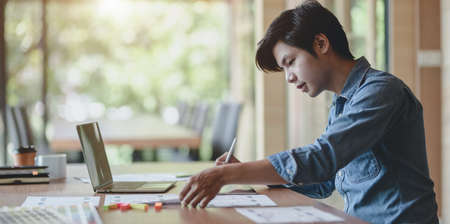 Professional male UI web developer working on his project about UX template while using laptop computer in the officeの写真素材