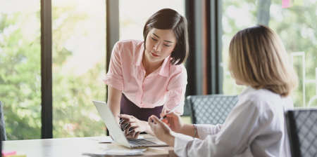 Two young professional UI web developers working on their project with laptop computer in modern office roomの写真素材