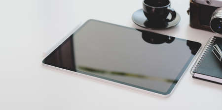 Cropped shot of photographer workplace with tablet and office supplies on white desk with copy spaceの写真素材