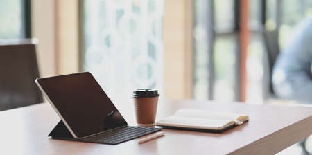 Modern workplace with tablet and a cup of coffee on wooden table in comfortable atmosphere