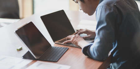 Young UX web developer working on the smartphone templates on laptop computer in modern office roomの写真素材
