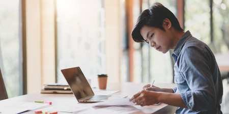 Young male UI web developer working on his smartphone templates with tablet in modern office