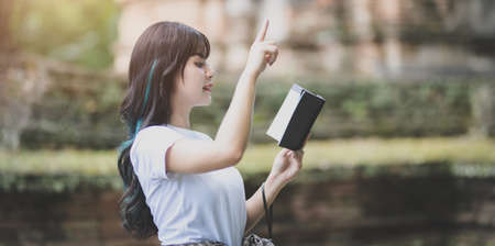 Young female traveler reading the travel guide book while traveling in ancient historical placesの写真素材
