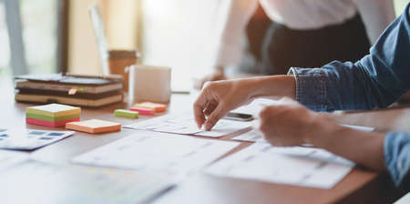 Close-up view of young professional UI web designer working on his project with his coworkers in the...