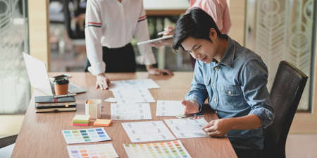 Group of young professional UI graphic designer discussing on their smartphones templates togetherの写真素材