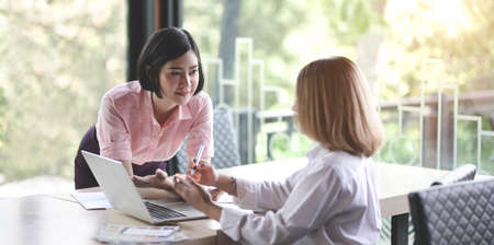 Two young professional UI graphic designers discussing on their smartphones templates with laptop computerの写真素材