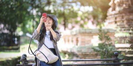 Young asian traveler taking the photo of the old temple while visiting the ancient historical places during the vacationの写真素材