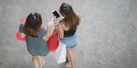 Top view of two beautiful women chatting and walking after finish shopping at the mallの写真素材