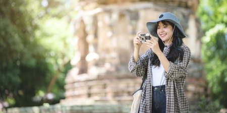 Adorable asian traveler taking the photo of the old temple while visiting the ancient historical places during the vacationの写真素材