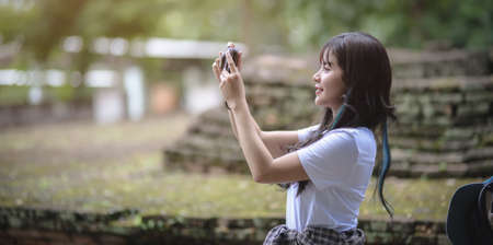Beautiful asian traveler taking the photo of the old temple while visiting the ancient historical places during the vacationの写真素材