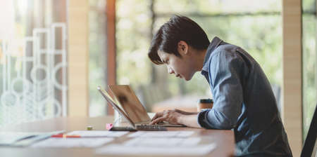 Side view of young passionate UX web developer working on his current project while typing on laptop computerの写真素材