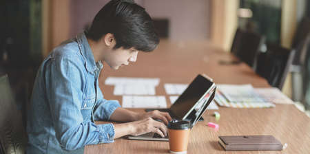 Professional male UX web designer working on his new smartphone templates project while using laptop computerの写真素材