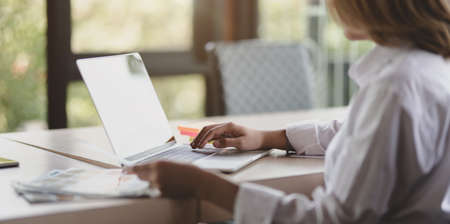 Close-up view of professional UI web designer working on her upcoming smartphone templates while typing on laptop computerの写真素材