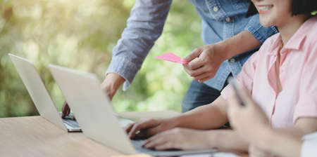 Close-up view of young professional UI graphic designer team brainstorming on their smartphones templates with laptop computerの写真素材