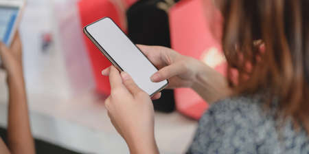 Cropped shot of young female checking her blank screen smartphone at the shopping mallの写真素材