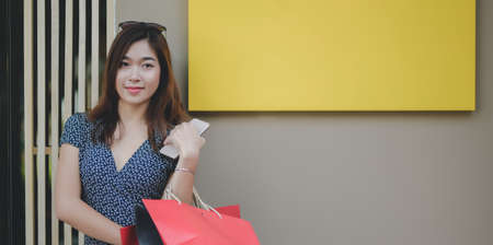 Portrait of young beautiful asian woman standing outside the mall after spend time shopping at the mallの写真素材