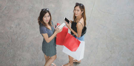 Portrait of two beautiful women smiling to the camera while walking outside the shopping mallの写真素材