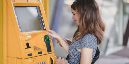 Two young asian female withdrawing the money from a bank card using ATM machine at the mallの写真素材