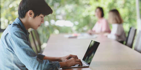 Young male UI web developer working on his project about UX template with his coworker in the backgroundの写真素材