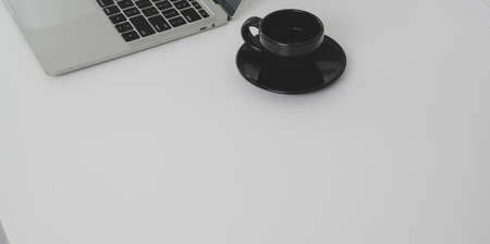 Top view of minimal workplace with laptop computer and coffee cup with copy space on white table backgroundの写真素材