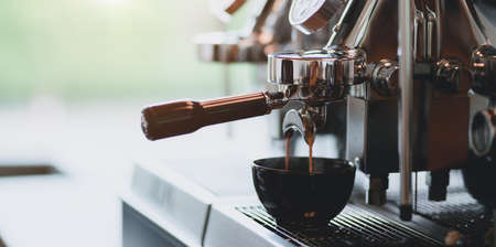Close-up view of espresso pouring from espresso coffee machine into a coffee cup in the coffee shopの写真素材