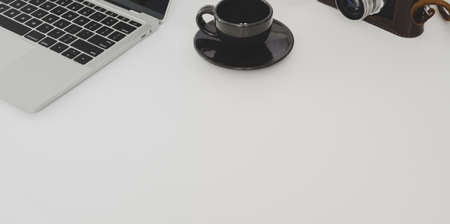 Top view of minimal workplace with laptop computer and coffee cup with copy space on white table backgroundの写真素材