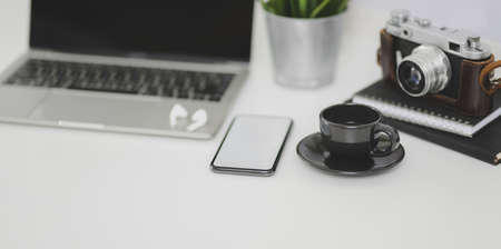 Modern photographer workplace with laptop computer, smartphone and office supplies on white deskの写真素材