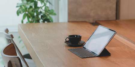 Blank screen tablet and a cup of coffee in comfortable workplace with a relaxing atmosphereの写真素材