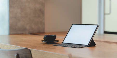 Blank screen tablet and a cup of coffee in comfortable workplace with a relaxing atmosphere