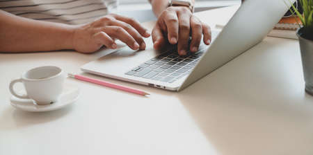 Close-up view of man typing on laptop computer in cozy comfortable workplaceの写真素材
