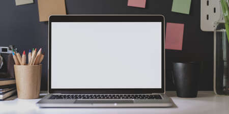 Open blank screen laptop with office supplies in dark trendy workplace with colourful sticky notesの写真素材