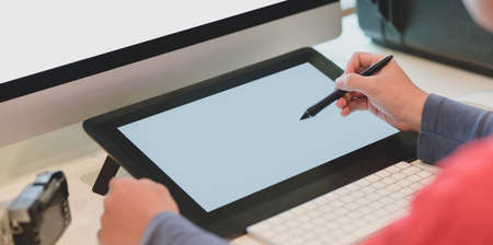 Close-up view of young male photographer editing his images on digital tablet in his workplaceの写真素材