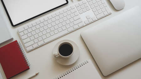 Top view of modern workplace with laptop computer, coffee cup and other office accessories on white table backgroundの写真素材